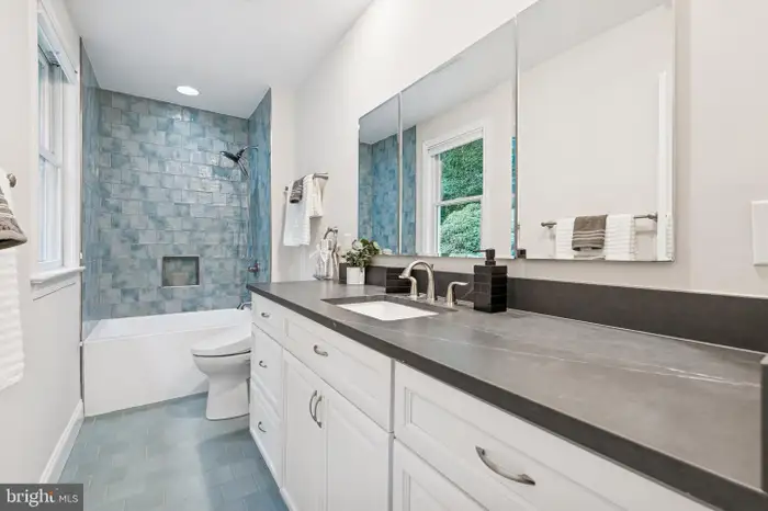 Modern bathroom with blue tile shower, white cabinets, and dark gray countertop