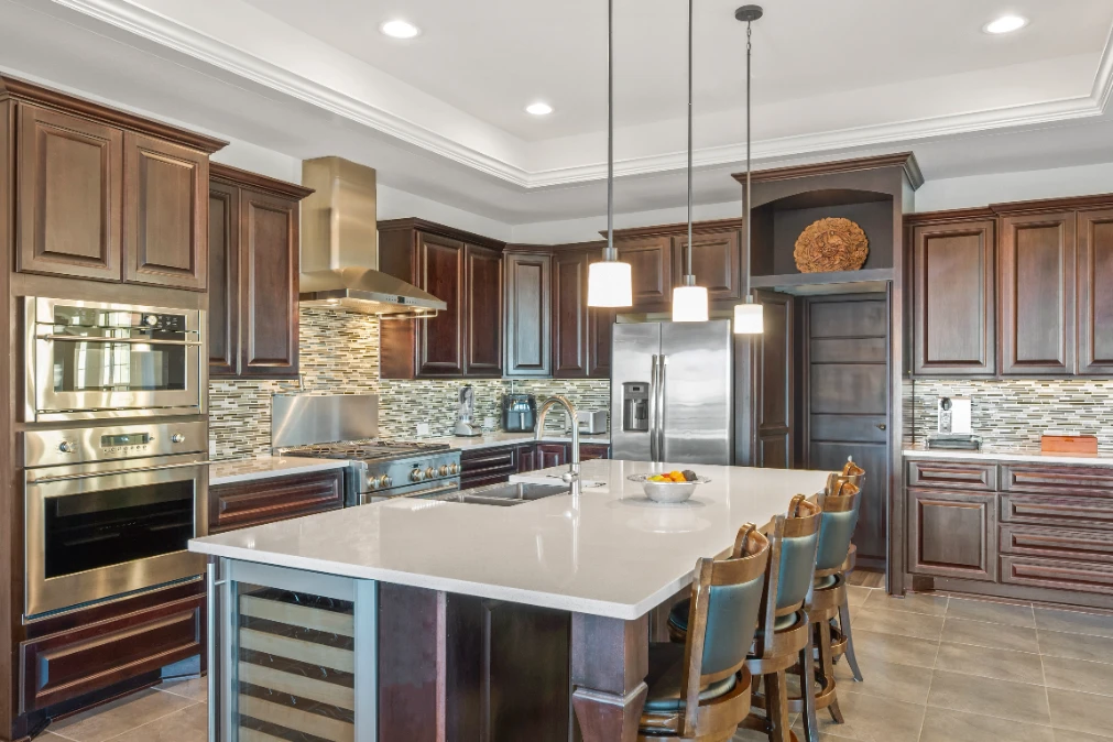 Luxury kitchen with dark wood cabinets, large island, stainless steel appliances, and pendant lights